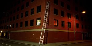 Leiter an Hauswand, leere Straße, Nacht